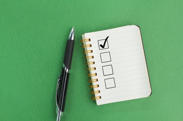 Photo pen and book with correct marks the concept of a checklist or checkup checklist sheet right sign