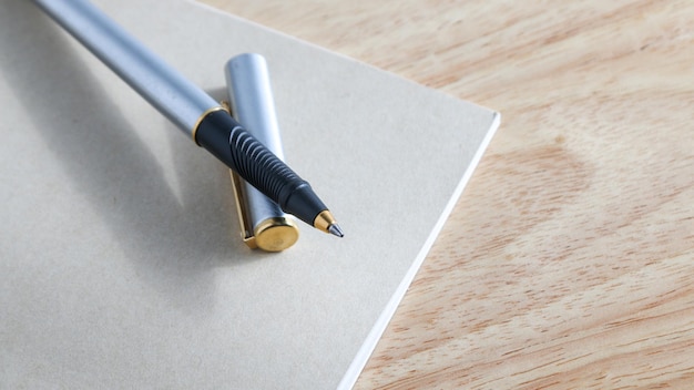 Pen and book on wood background