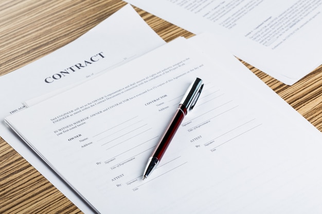 Pen and contract papers on wooden desk