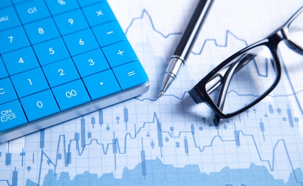 Pen eyeglasses and calculator on the financial graphs