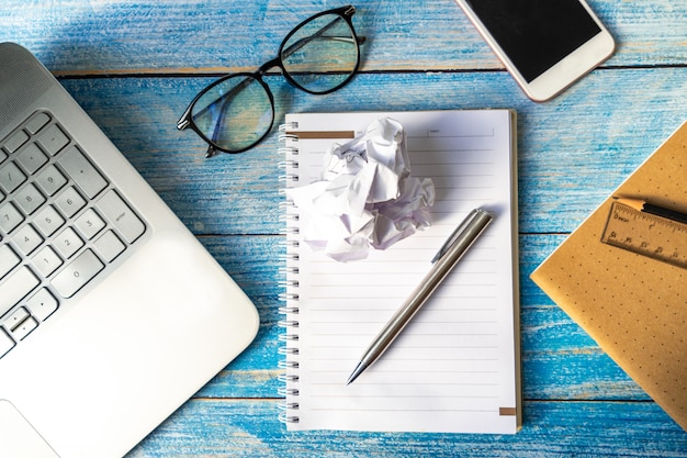 Pen and eyeglasses with laptop on wooden table.