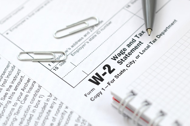 The pen and notebook on the tax form W-2 Wage and Tax Statement.