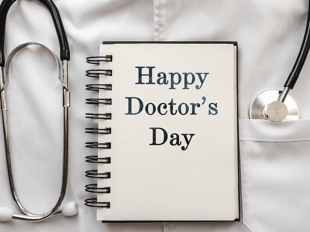 Photo pen, stethoscope, face mask and eye glasses lying on a medical gown. happy doctor's day. close-up, no people. congratulations for relatives, friends and colleagues