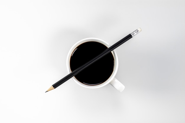 Pencil on coffee cup at white desk.