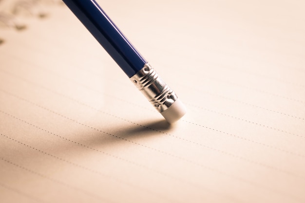 Pencil eraser removing a written mistake on a piece of paper, delete, correct, and mistake concept.