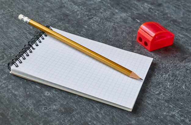 Pencil lies on the notebook next to the sharpener,