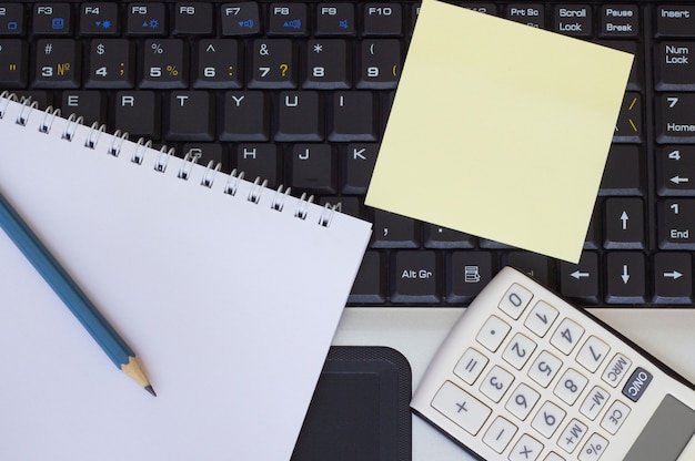 Pencil, notebook and calculator on laptop keyboard