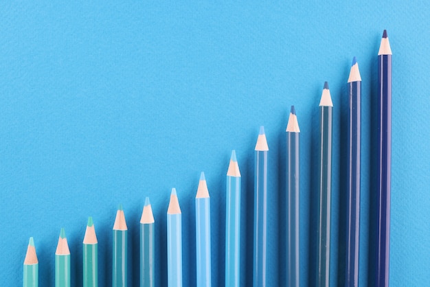 Pencils of different shades lie on blue background