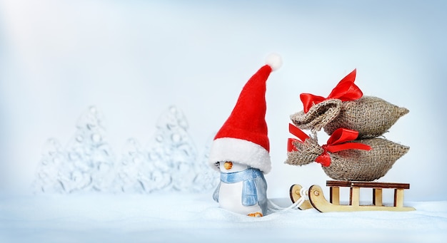 A penguin in a Santa hat carrying Christmas gifts on a sleigh