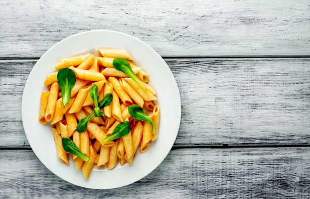 Photo penne pasta in plate on wood background