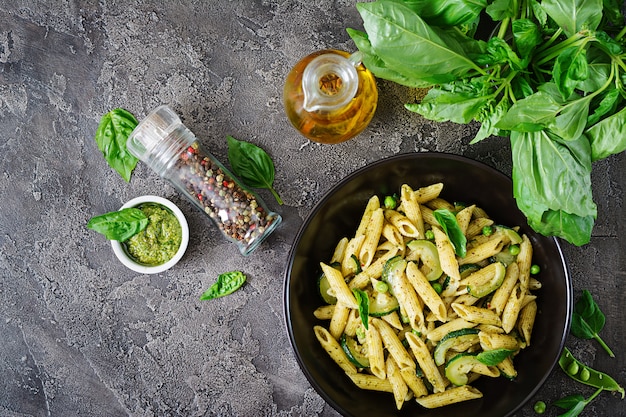 Photo penne pasta with  pesto sauce, zucchini, green peas and basil. italian food.