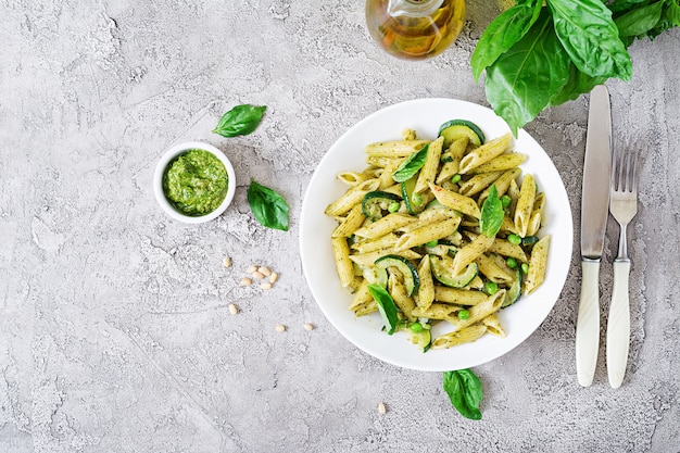 Penne pasta with  pesto sauce, zucchini, green peas and basil. Italian food.