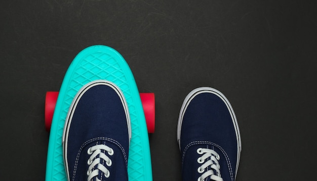 Penny board and sneakers on a black background. Top view. Retro style