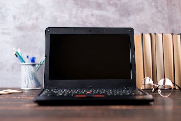 Pens, apple, pencils, books, laptop and glasses on the table, on chalkboard background