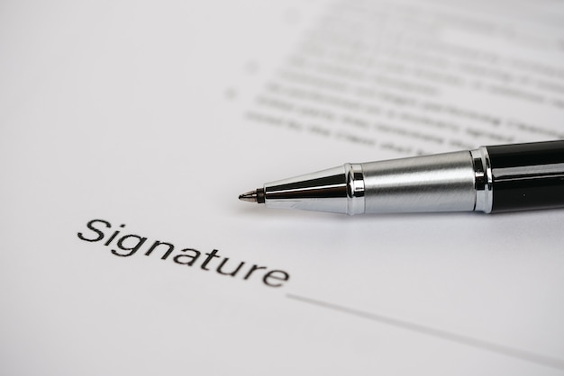 Pens and contract documents are placed on the desk.