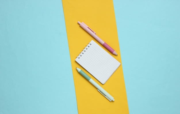 Pens with notebook closeup on blue yellow background