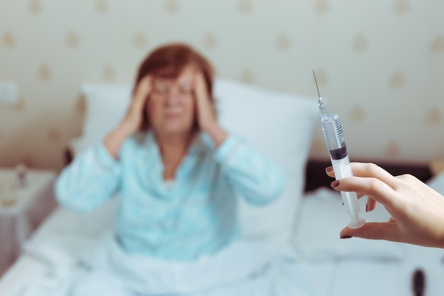 Pensioner woman in bed got syringe coronavirus in europe elderly people in zone of risk