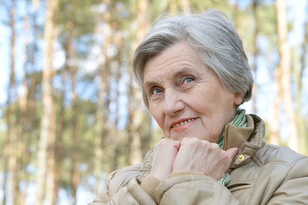 Pensive aged woman walking in the forest in autumn