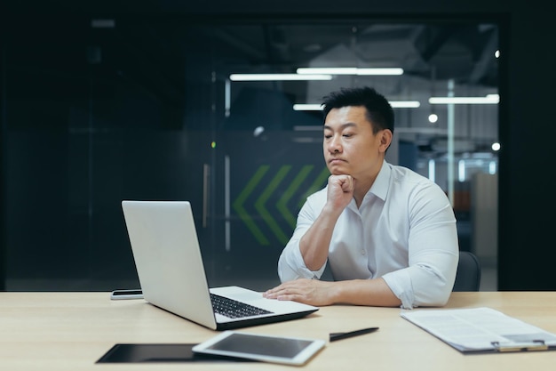 Pensive asian businessman working in modern office man thinking about decision experienced director