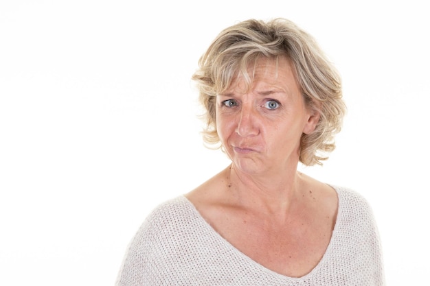 Pensive beautiful senior grimacing woman looking posing in white copy space wall background