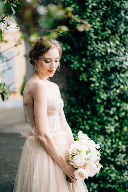 Pensive bride in pink dress with a bouquet of flowers