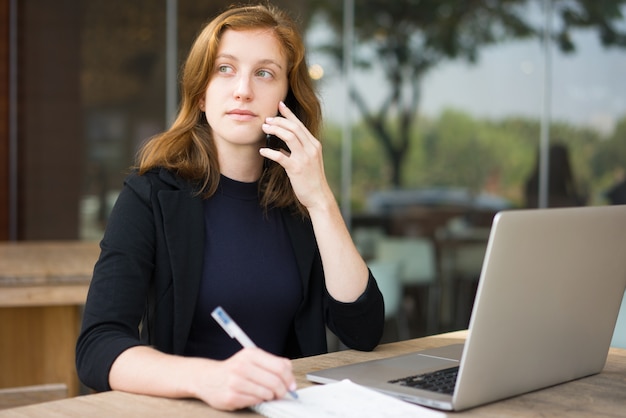 Pensive Business Woman Speaking on Phone at Cafe