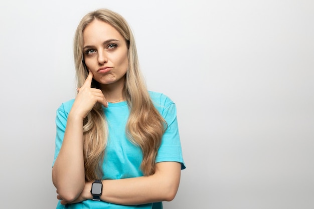 Pensive girl in a blue tshirt on a white background