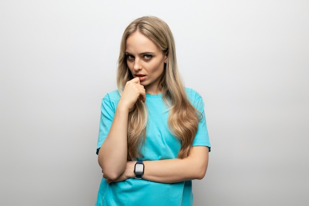 Pensive girl in a blue tshirt on a white background