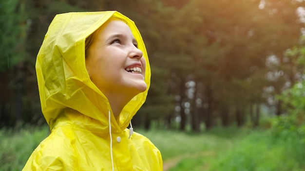 Pensive girl looks away enjoying rainy weather in forest