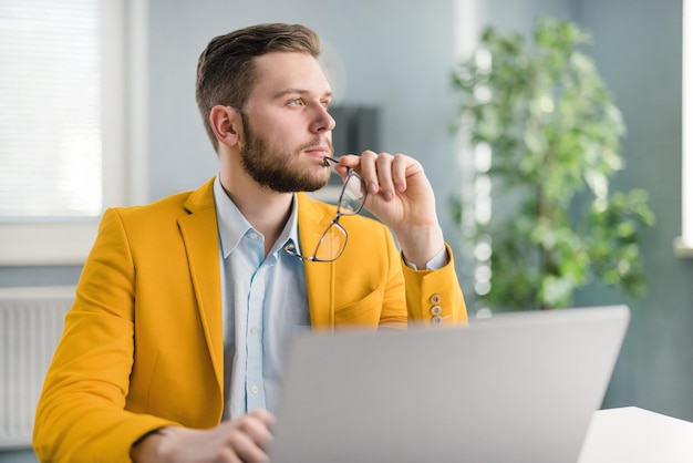 Pensive male employee with laptop looking