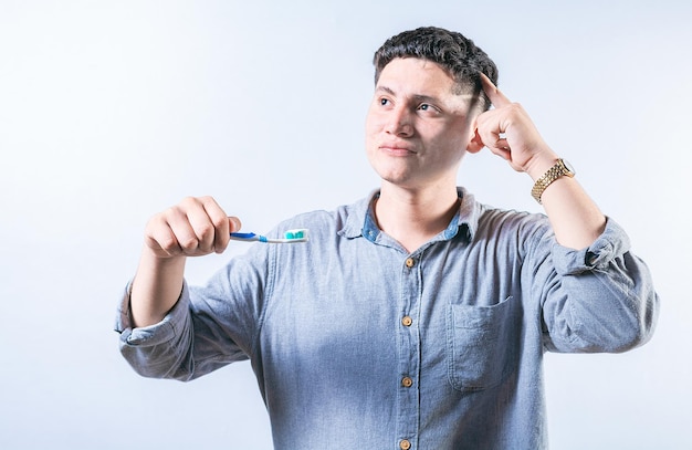 Pensive man holding toothbrush isolated Thoughtful person holding toothbrush and looking up isolated