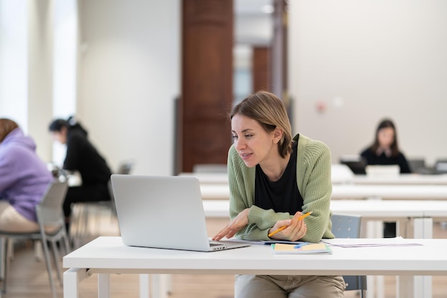 Pensive middleaged woman studying in library on laptop mature female student watching webinar