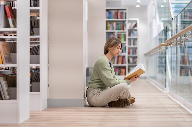 Pensive middleaged woman with book spending free time in library enjoying reading