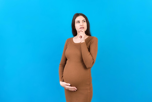 Pensive pregnant woman choosing name for baby on colored background Dream and Happy Pregnant Woman Thinking Imagining Motherhood Life Copy Space