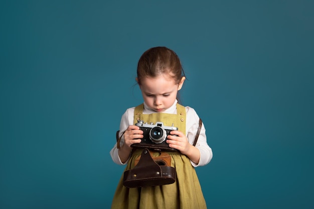 Pensive serious little girl intends to learn to photograph