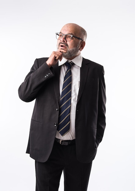 Pensive thoughtful Indian old businessman. Touching chin. Asian senior bald and bearded business person thinking against white background