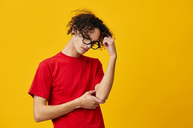 Pensive thoughtful myopic young student man in red tshirt funny eyewear posing isolated on over yellow studio background The best offer with free place for advertising Education College concept