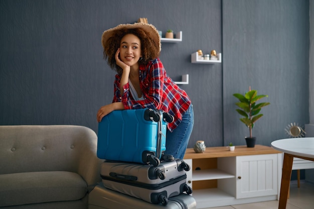 Pensive woman in sunhat with travel suitcase