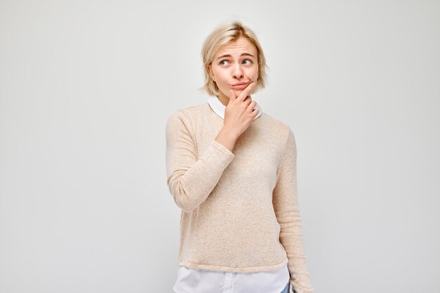 Pensive woman with hand on chin looking away isolated on white background