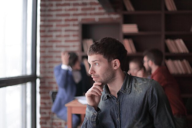 Photo pensive young designer looking out the office window