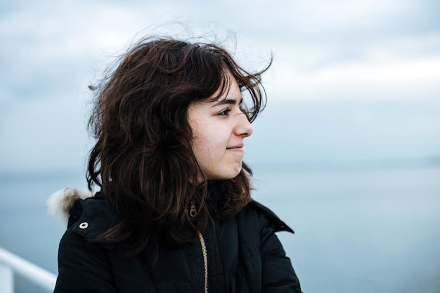 Pensive young girl looking to the sea from boat Teenager girl at ferryboat Cold grey sea