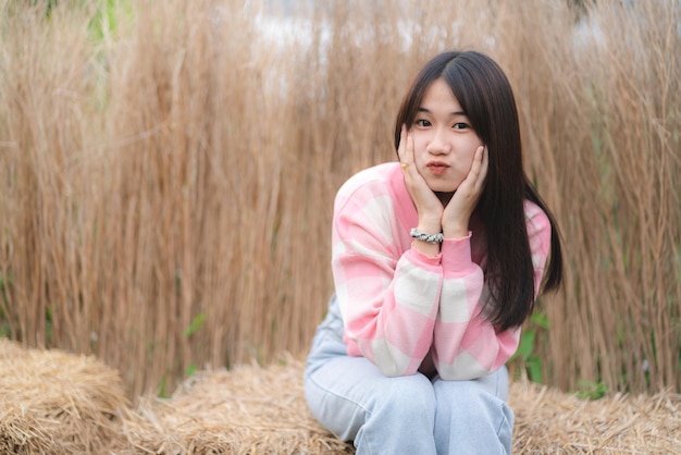 Pensive young woman sitting in the fields and thinking about future while looking away