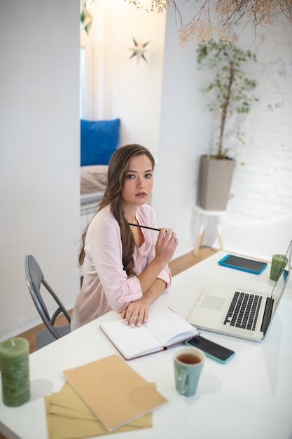 Pensive young woman sitting in her office while thinking about her work