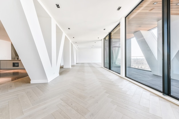 Penthouse interior of studio room with glass walls and terrace viewing cityscape in sunlight