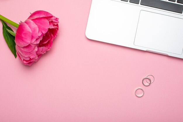 Peony flower, laptop and rings.Fashion summer colour.