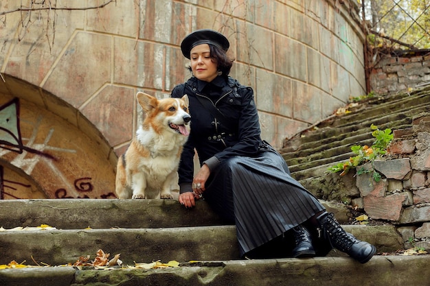 People, animal, beauty, fashion, lifestyle and color concept - Outdoor full body portrait of young beautiful happy smiling girl posing on street. girl with dog corgi. Lady wearing stylish clothes