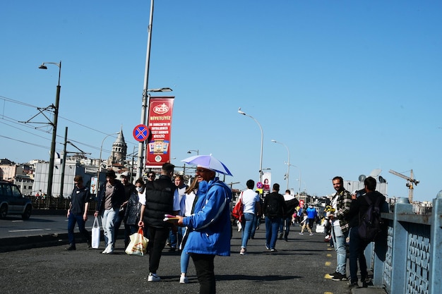 People are walking on the bridge A man sells a rain hat April 11 2022 Istanbul Turkey