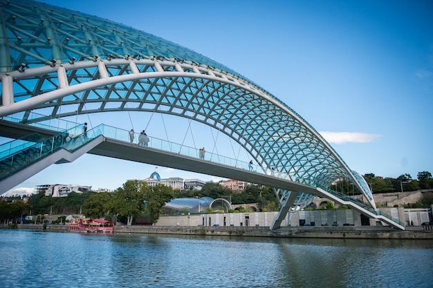 People on bridge of peace over kura river against blue sky