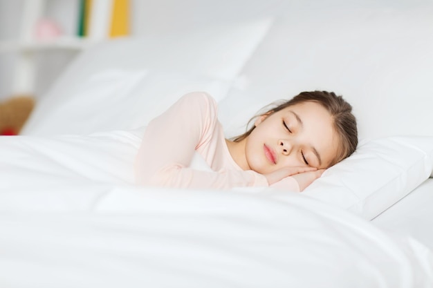 people, children, rest and comfort concept - girl sleeping in bed at home