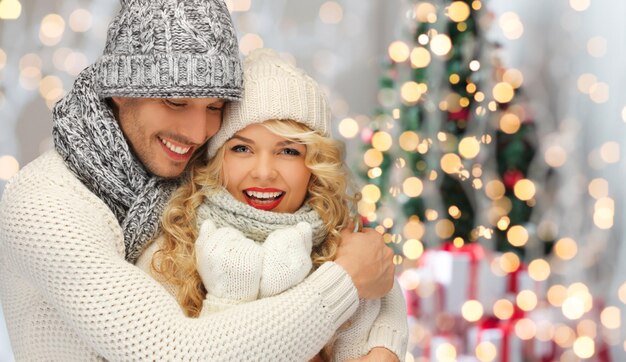 people, christmas, holidays and new year concept - happy family couple in winter clothes hugging over lights background